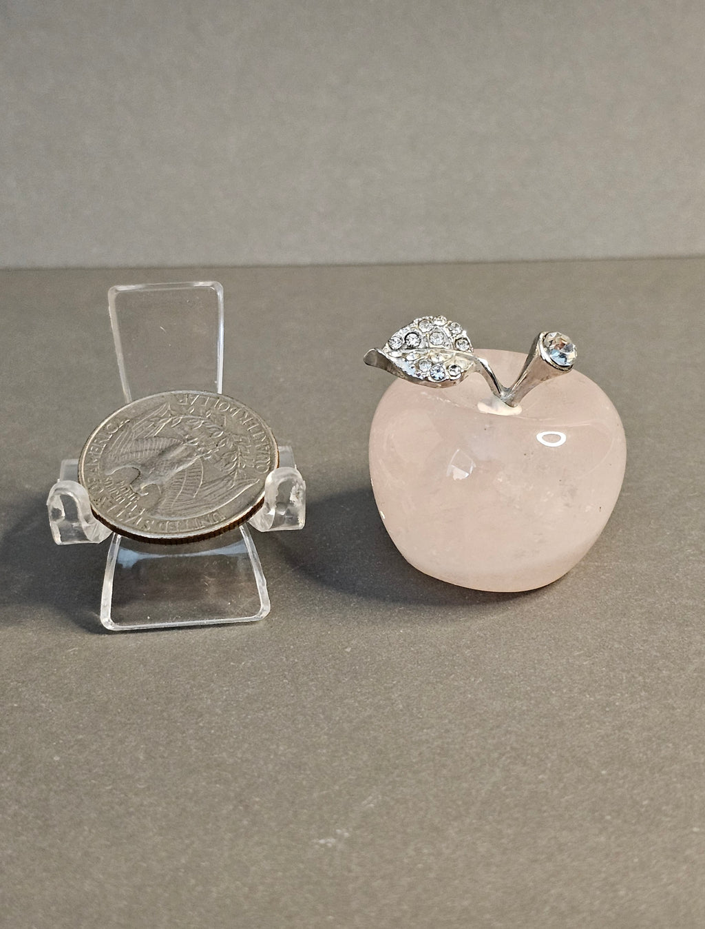 Rose Quartz apple carving shown with quarter for size comparison.