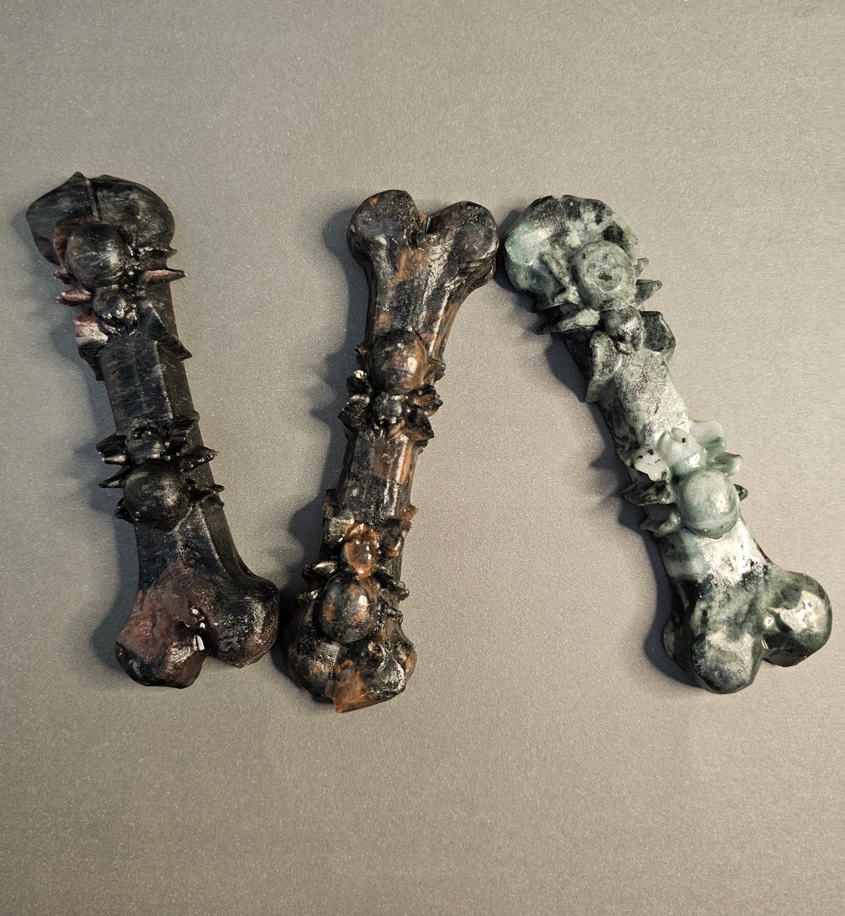 Three carvings of bones that have spiders carved on them.