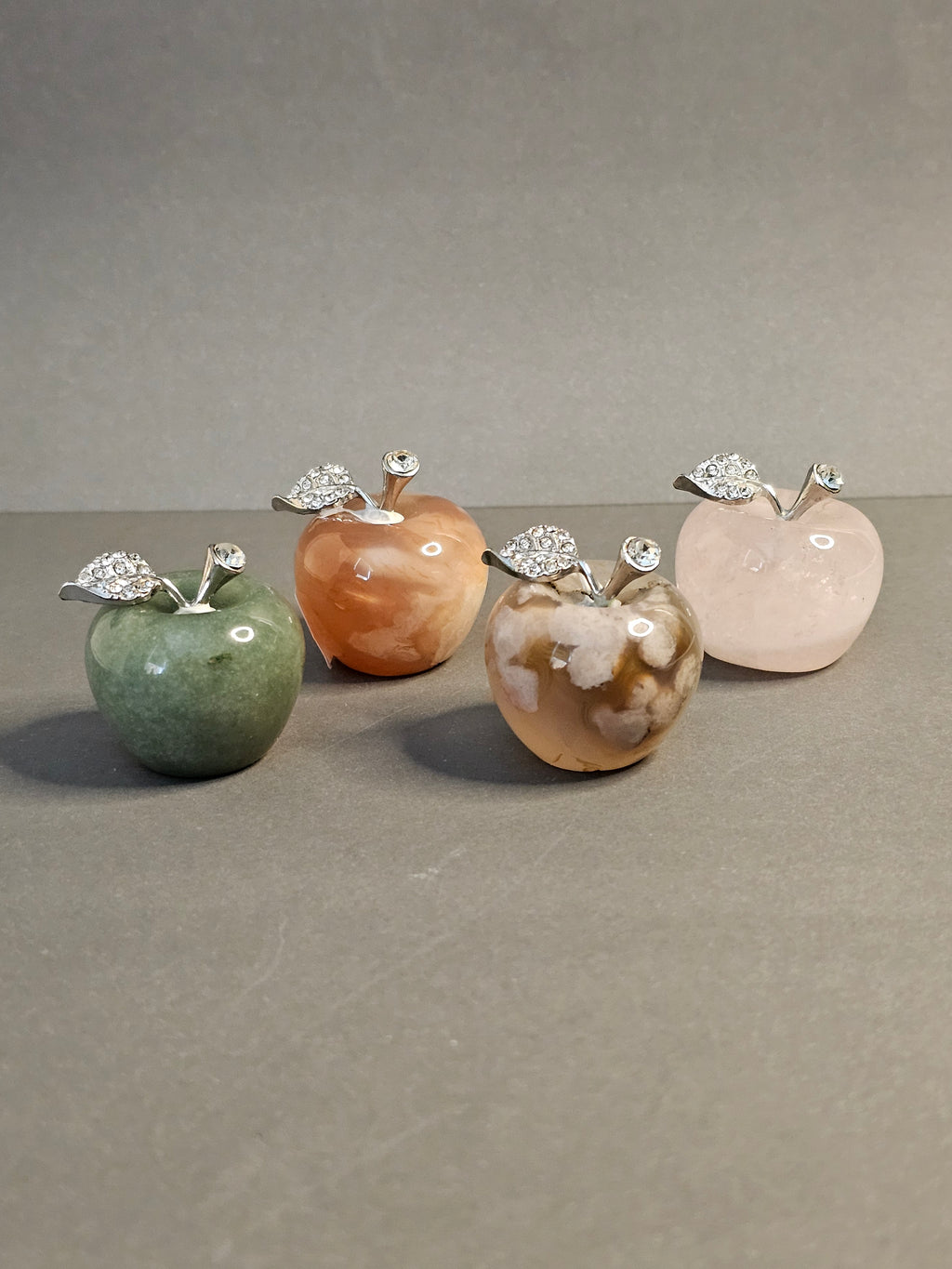 Four apple carvings made up of various crystal types.