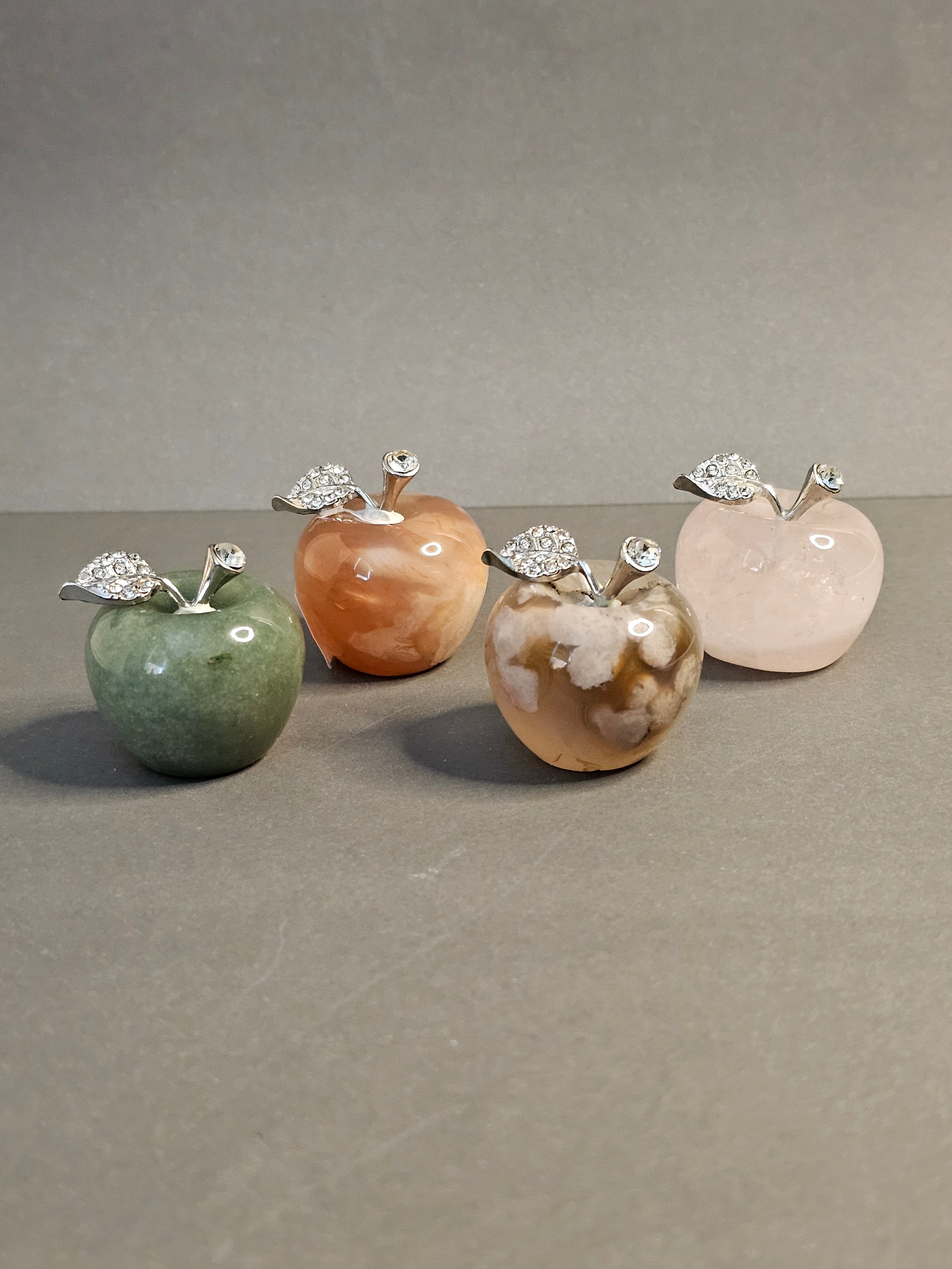 Four apple carvings made up of various crystal types.