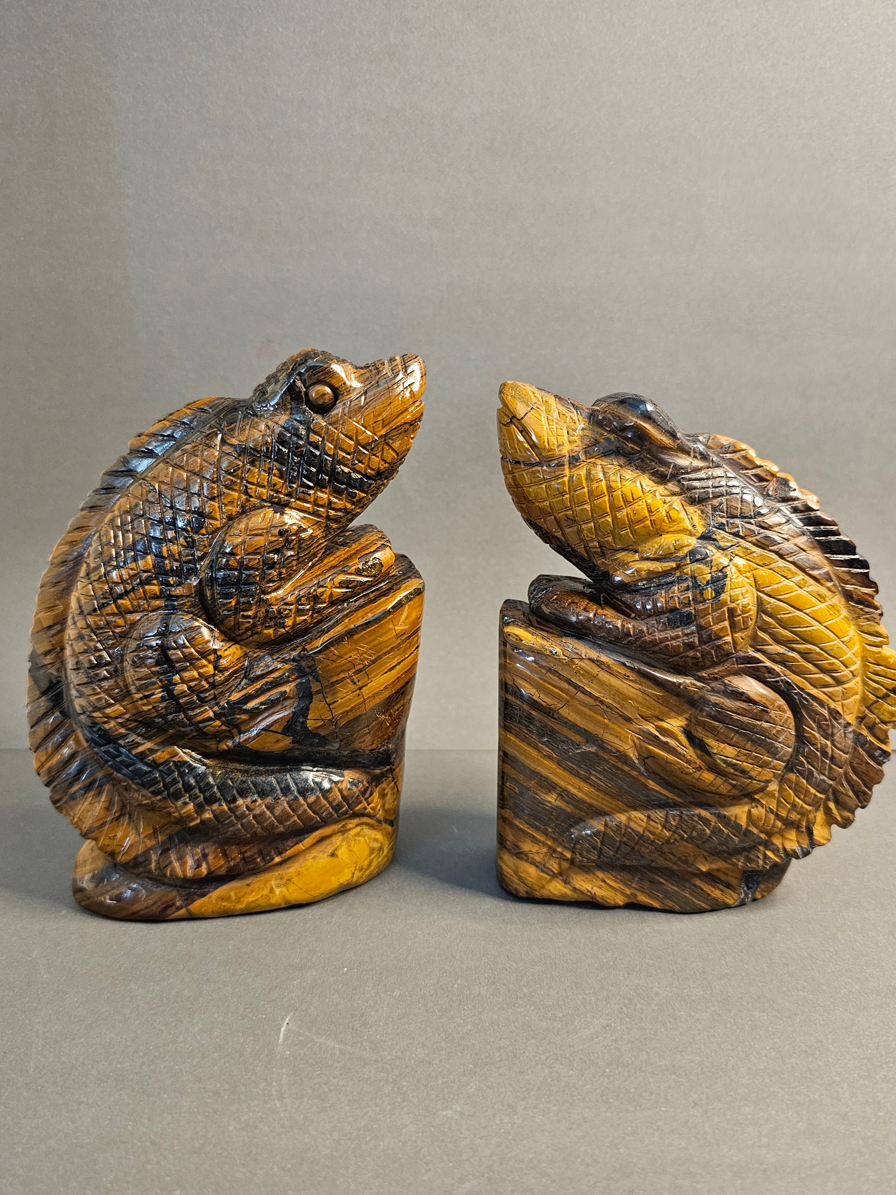 Two Tiger's Eye lizard carvings facing each other.